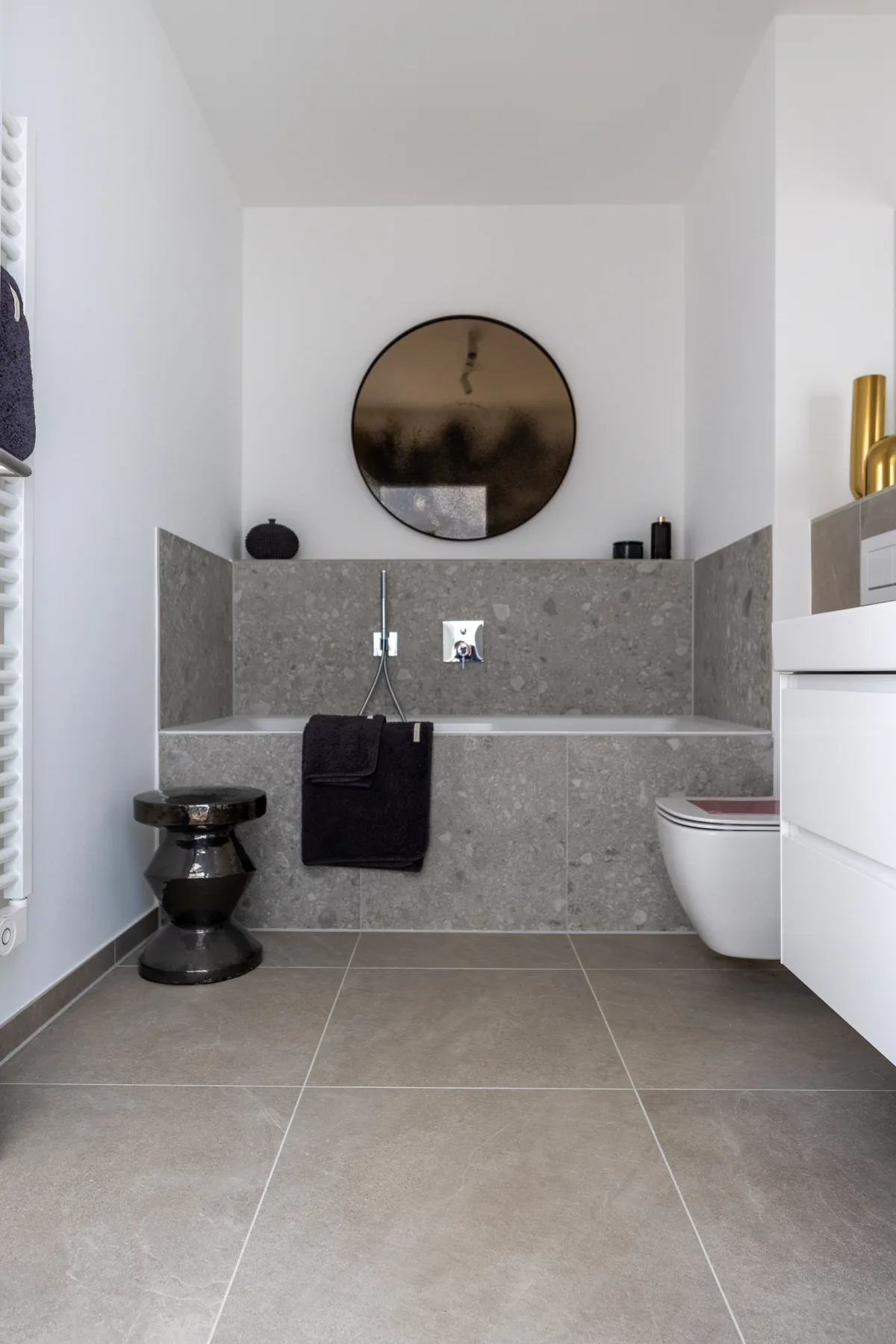 Badezimmer mit rundem Spiegel und gefliester Vorwand