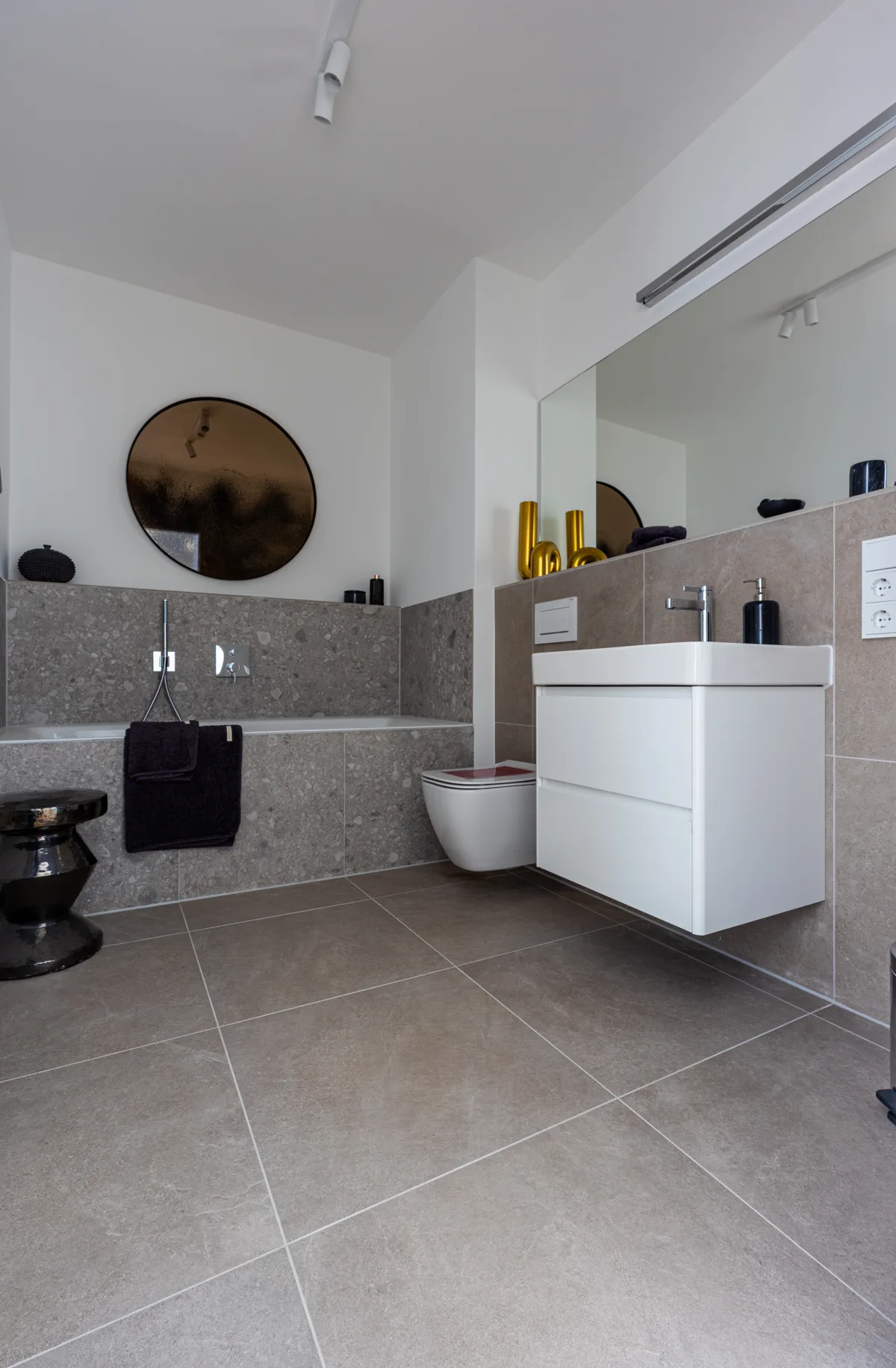 Badezimmer mit graubeigen Boden- und Wandfliesen