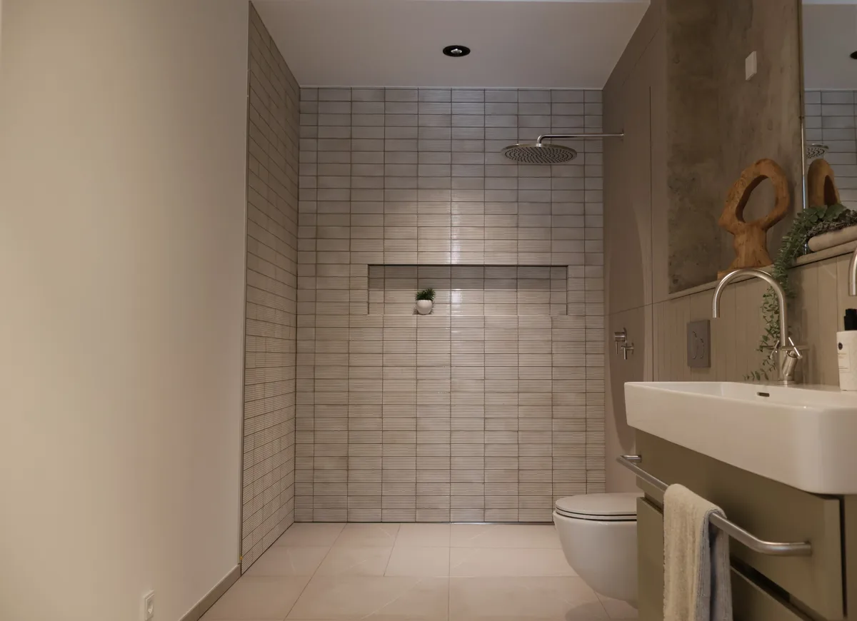 Badezimmer mit bodengleicher Dusche und kleinteiligen Wandfliesen