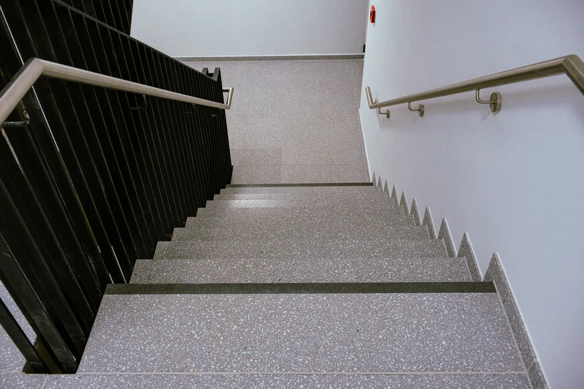 Treppe mit grauen Stufen und dunklem Geländer